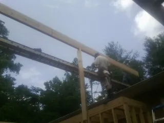 Carpenter setting a ridge beam over a new addition frame — Ice Dam Removal by Roofing Brothers in Turpin