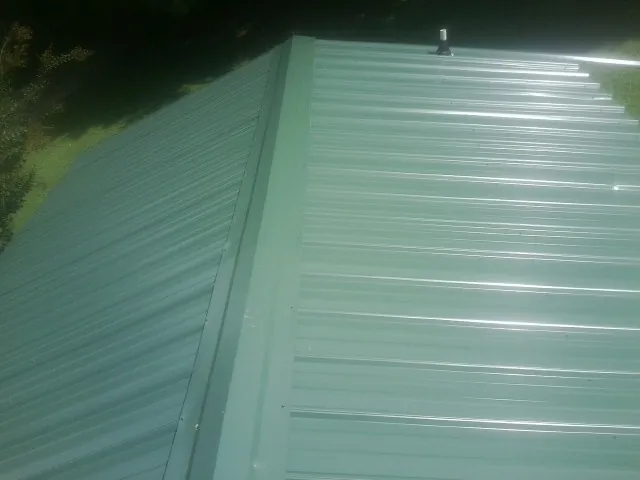 New green metal panels meeting at the ridge of a roof — Flat Roof Repair work by our crew in Turpin