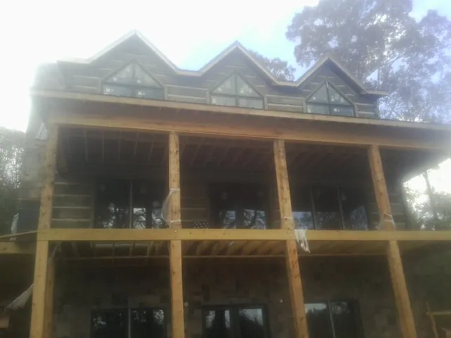 Dormers and porch framing on a large log home under construction — Roof Coating work by our crew in Turpin