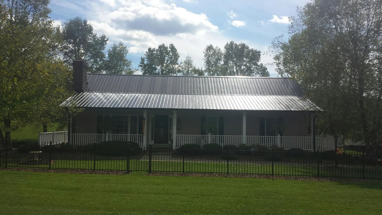 Gray metal roof on a brick ranch with a full width front porch — Gutter Guard Installation work by our crew in Turpin