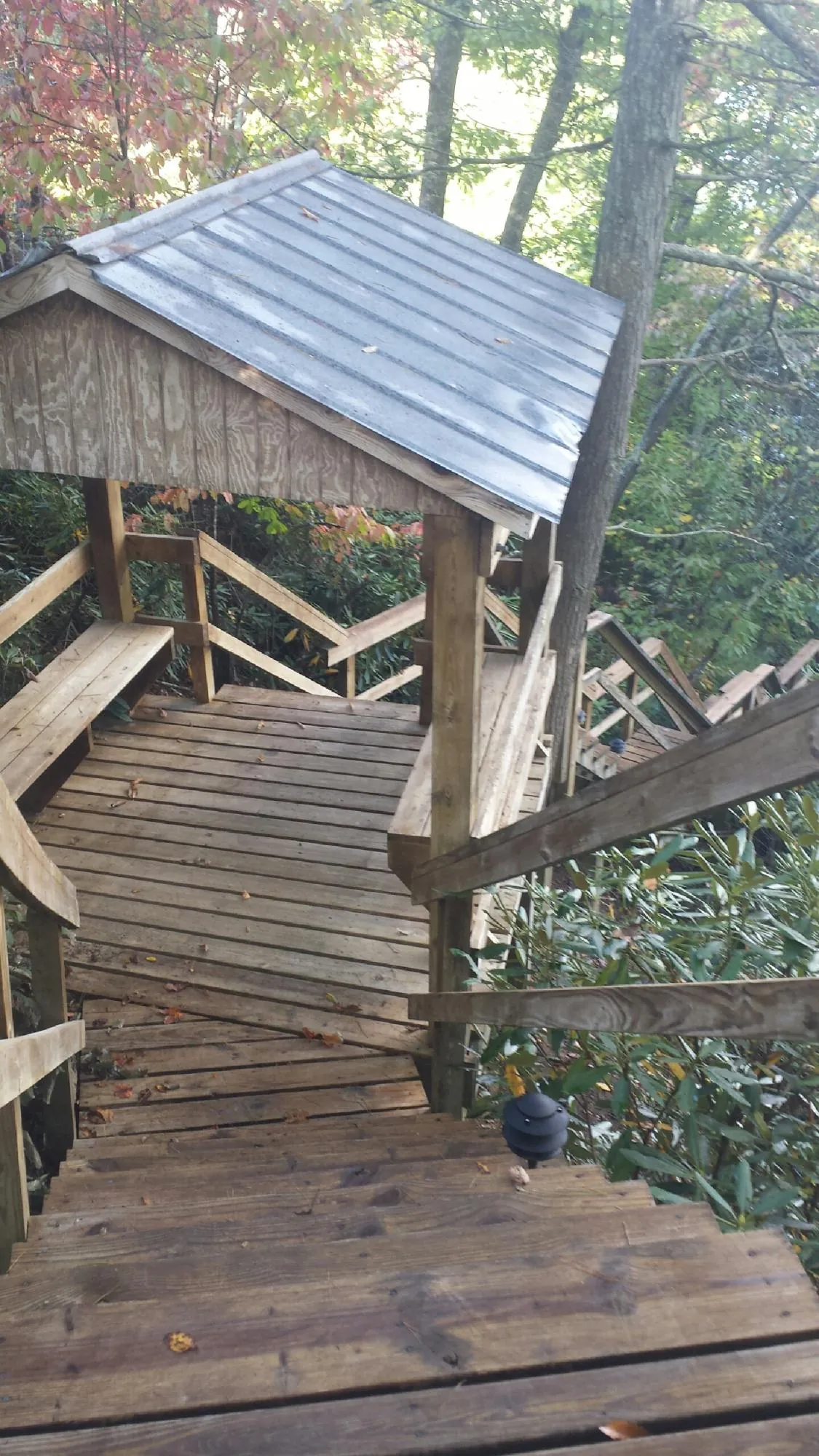 Metal roofed shelter over wooden steps on a wooded walkway — Skylight Repair & Installation work by our crew in Turpin