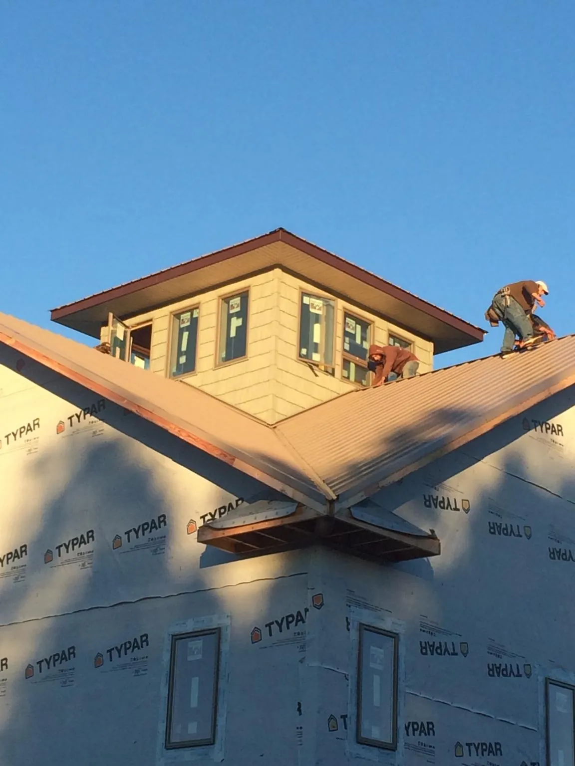 Roofers working around a rooftop cupola on a new metal roof at sunset — Roof Waterproofing in Turpin by Roofing Brothers